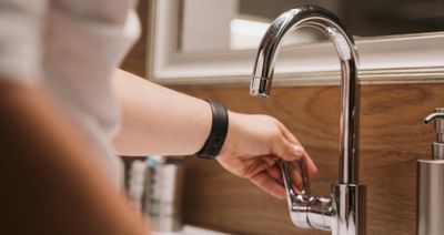 Hand reaching to turn on faucet following exceptional service from Mr Perfect Plumbing