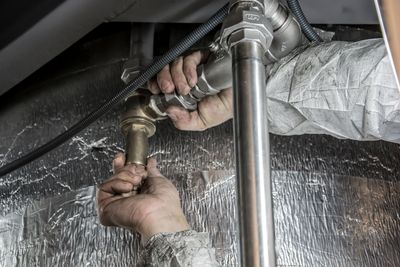 Mr Perfect Plumbing technician tightening a supply line fitting under a sink in a Denver home