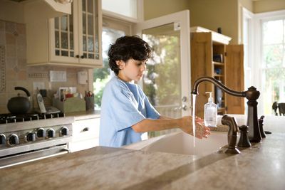 Boy washing his hands at the kitchen sink faucet in a Baker, Denver home