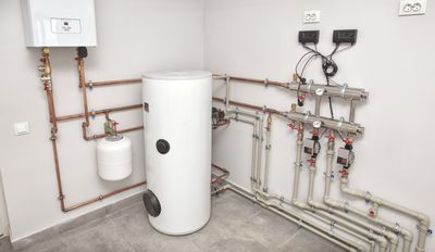 Residential water heater tank with copper pipes and boiler wall unit installed in a Baker, Denver home