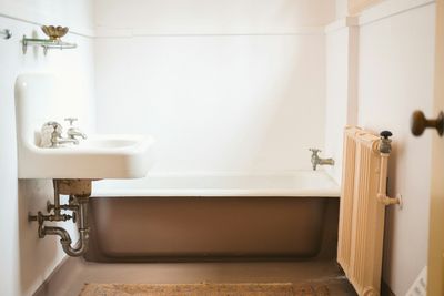 Vintage bathroom with pedestal sink, exposed drain pipes, and clawfoot tub in a Baker, Denver home