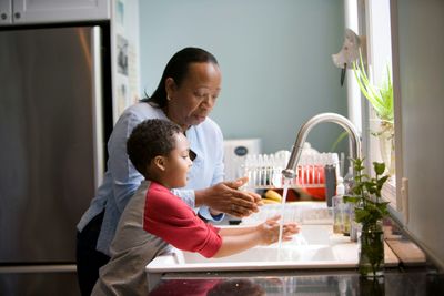 Adult helping child wash hands at the kitchen sink in a Capitol Hill, Denver home