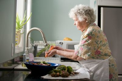 Older woman washing vegetables at the kitchen sink in a Cherry Creek, Denver home