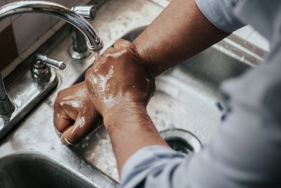 Man washing his hands at the kitchen faucet in a Congress Park, Denver home