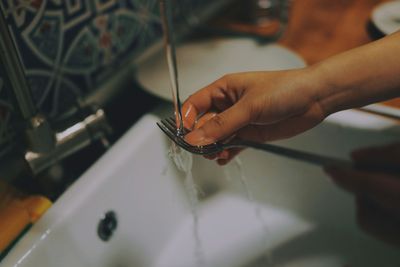 Person rinsing a fork under running water at the kitchen sink in a Congress Park, Denver home