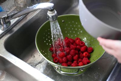 Raspberries rinsed under running water at a kitchen faucet in a Five Points, Denver home