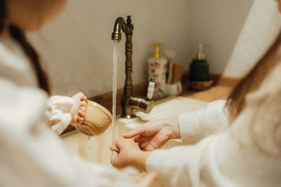 Two young girls washing their mugs at the kitchen sink in their Littleton home