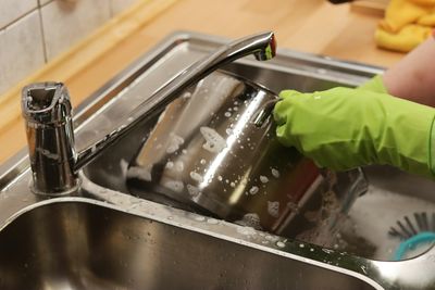 Person washing dirty pots in the kitchen sink of their Littleton home after receiving service from Mr. Perfect Plumbing