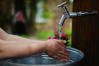 Child washing hands in Lone Tree home backyard under outdoor faucet