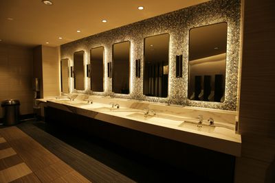 Upscale commercial restroom with multiple marble-top sinks and backlit mosaic tile in RiNo, Denver
