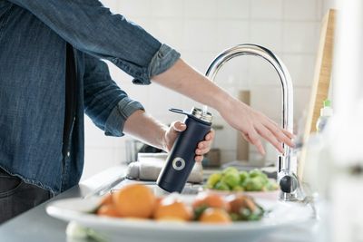 Person filling a water bottle at the kitchen faucet in a RiNo, Denver home