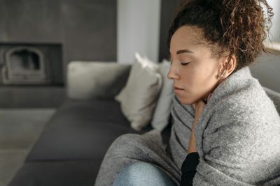 Woman cold and wrapped up in blanket at home due to faulty boiler