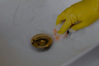 Gloved hand cleaning out a previously clogged drain